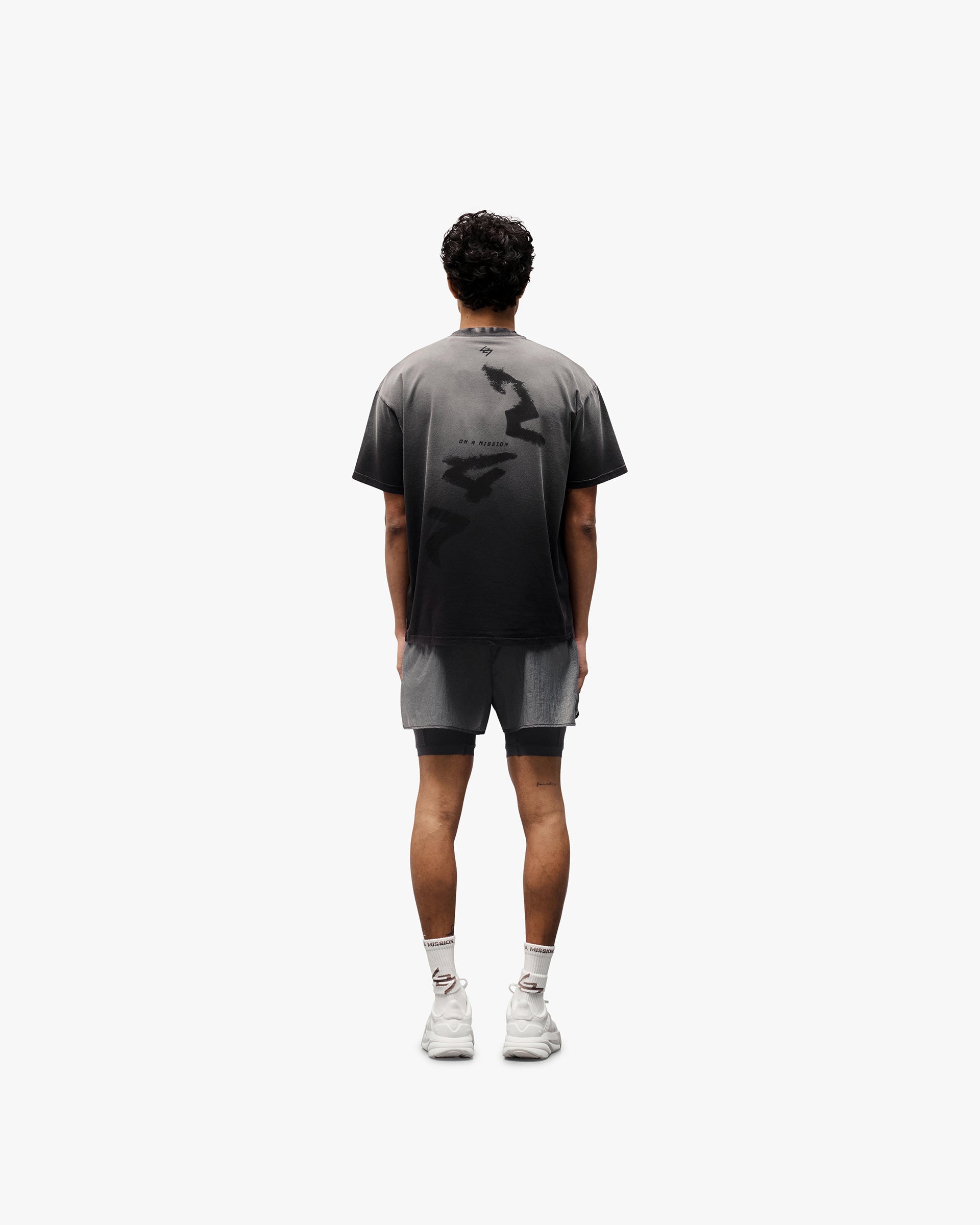 Man wearing an oversized black t-shirt on a plain white background | 247 Motion Oversized T-Shirt in Aged Black | Cotton blend t-shirt with graphic print | 247 T-Shirts | Represent Clo