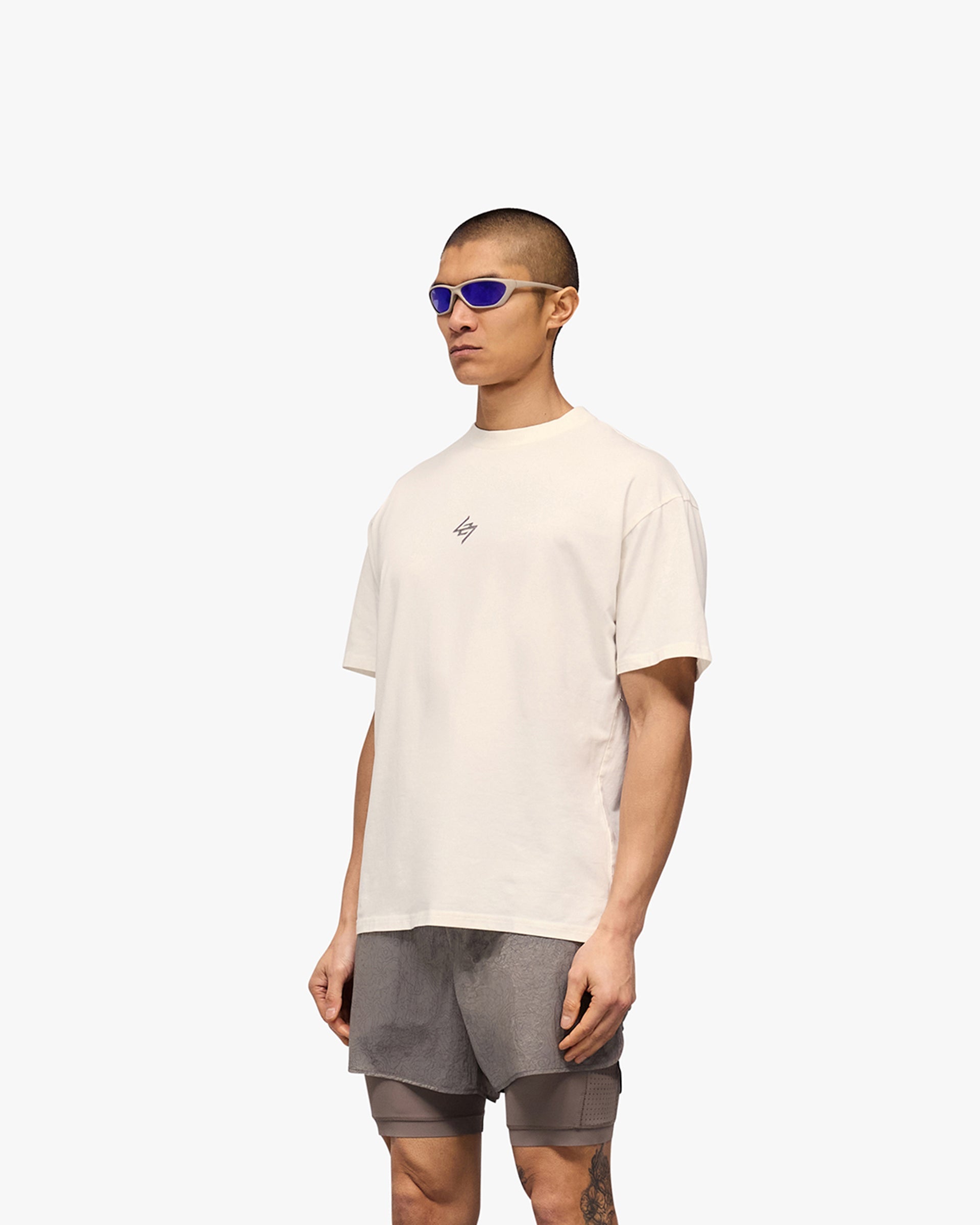 Man wearing an oversized white t-shirt on a plain white background | 247 Motion Oversized T-Shirt in Flat White | T-Shirt with 2 way stretch and graphic print | 247 T-Shirts | Represent Clo
