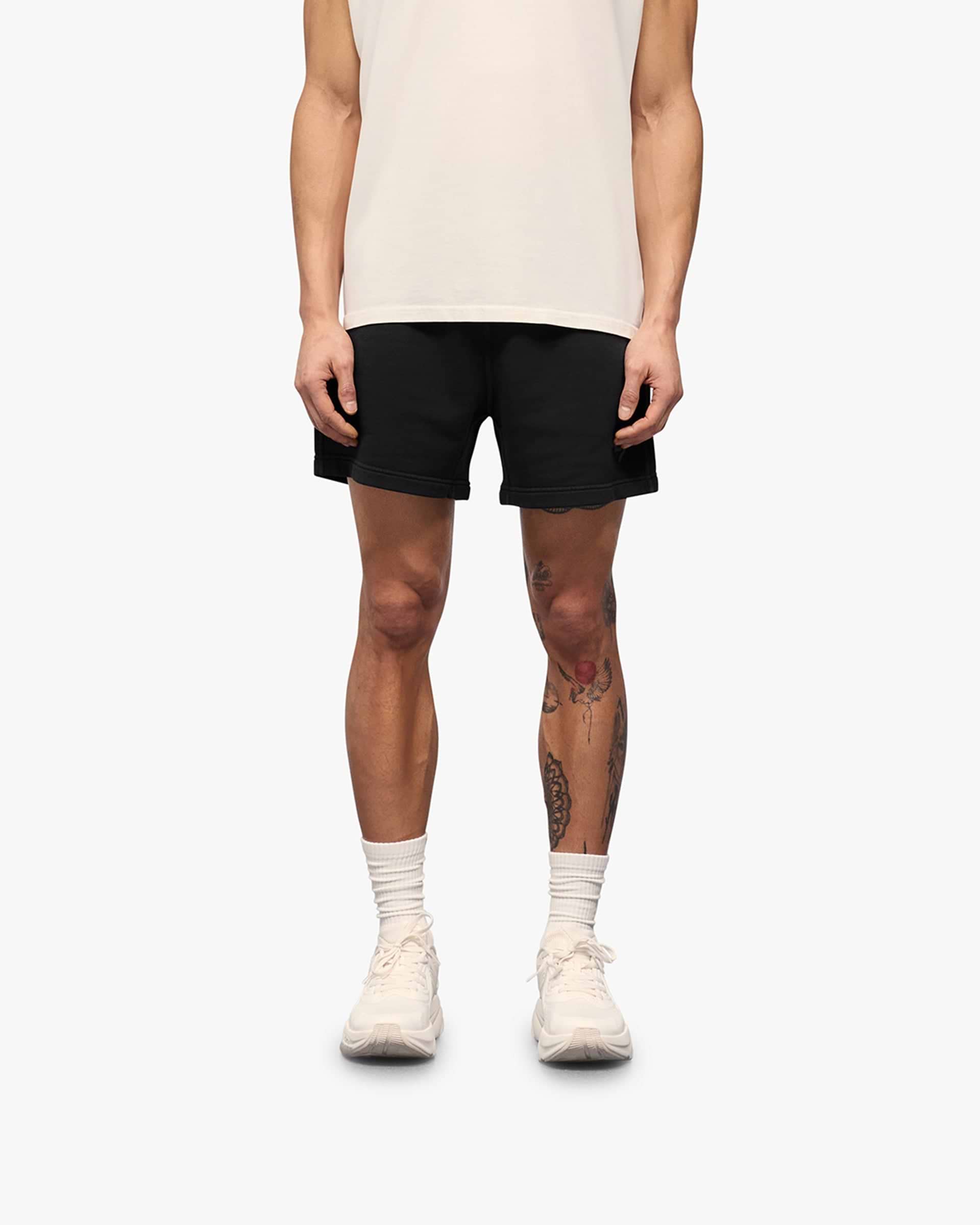 Man wearing aged black shorts on a plain white background | 247 Motion Shorts in Aged Black | Jersey shorts with elasticated waistband | 247 Shorts | Represent Clo