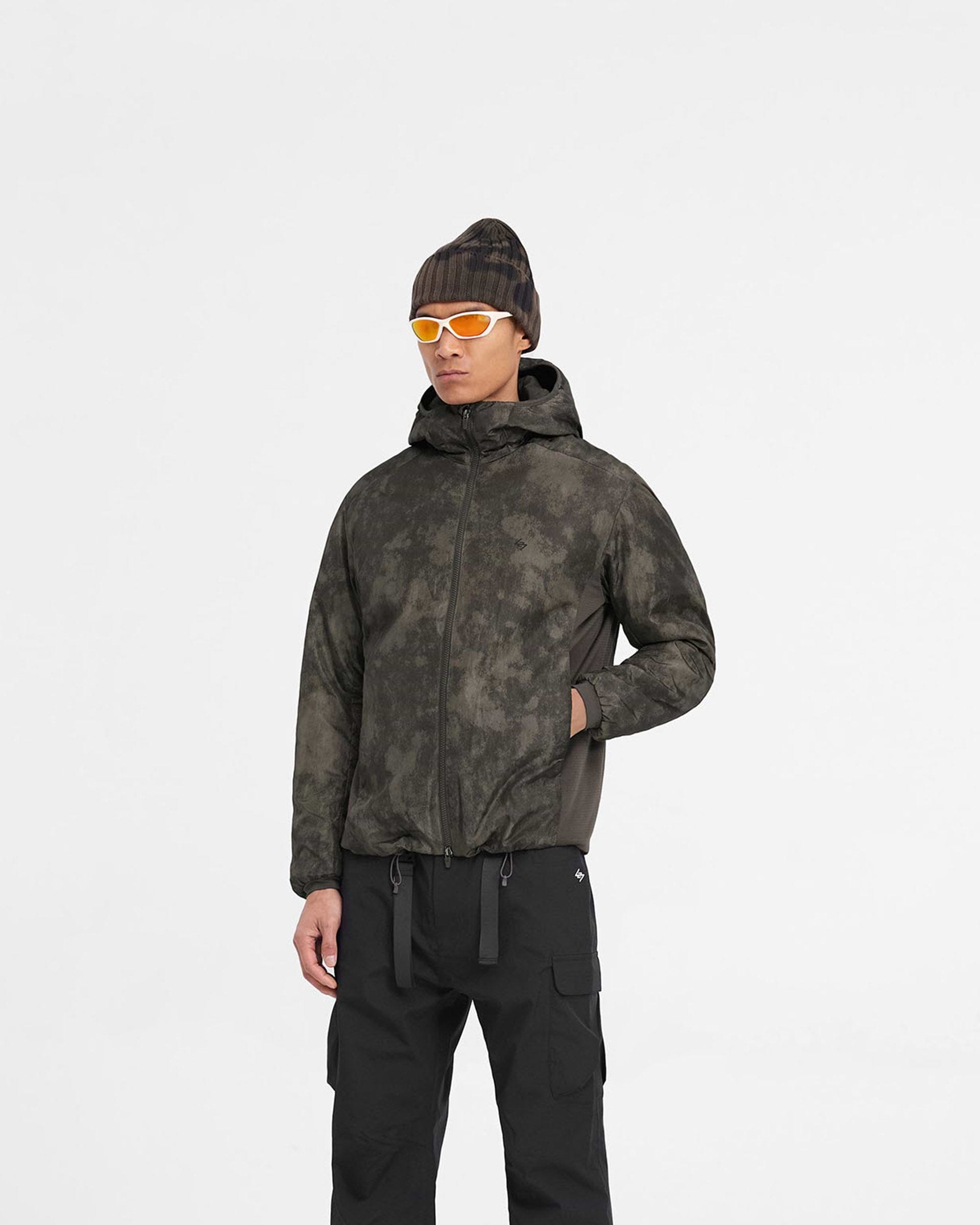 Man wearing a brown insulated jacket on a plain white background | Team 247 Insulated Jacket in Terrain | Insulated jacket with water repellent and adjustable hood | 247 Outerwear | Represent Clo