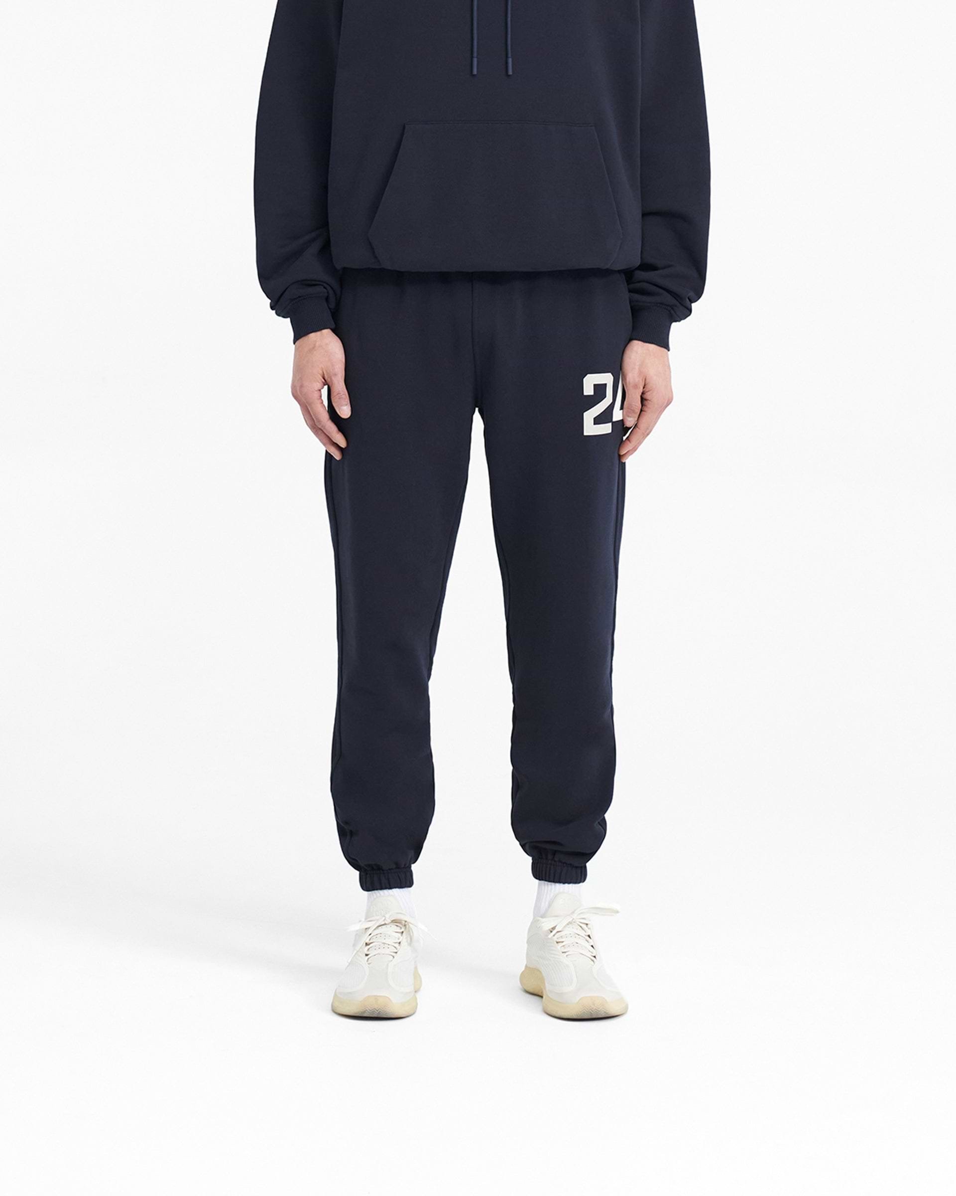 Man wearing navy sweatpants on a plain white background | 247 Sweatpant in Navy | Sweatpants with elasticated cuffs and drawcord waistband | 247 Pants | Represent Clo