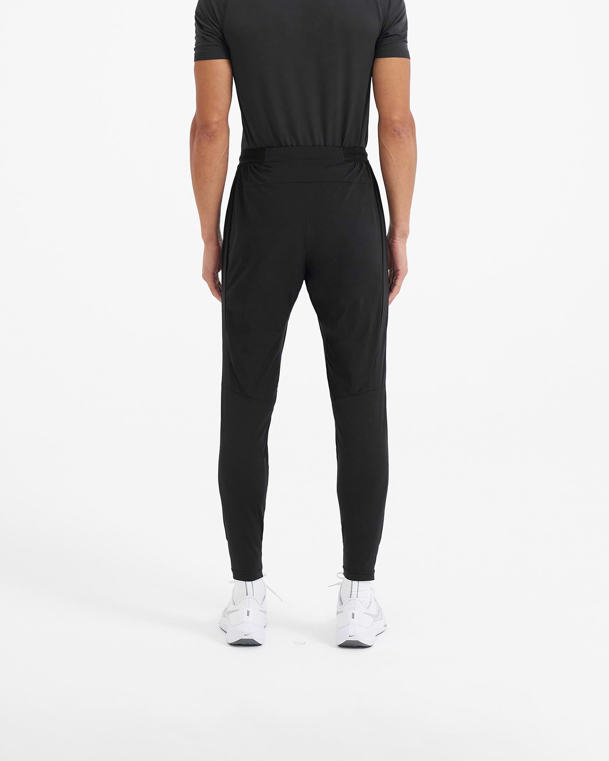 Man wearing black jogger pants on a plain white background | 247 Active Jogger in Black | 4-way stretch running pants with elasticated waistband | 247 Pants | Represent Clo