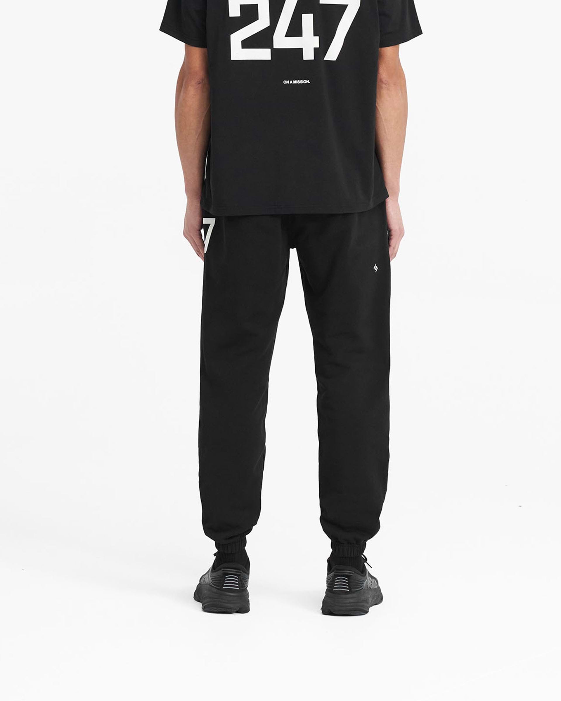 Man wearing black sweatpants on a plain white background | 247 Sweatpant in Black | Joggers with elasticated cuffs and internal drawcord | 247 Pants | Represent Clo