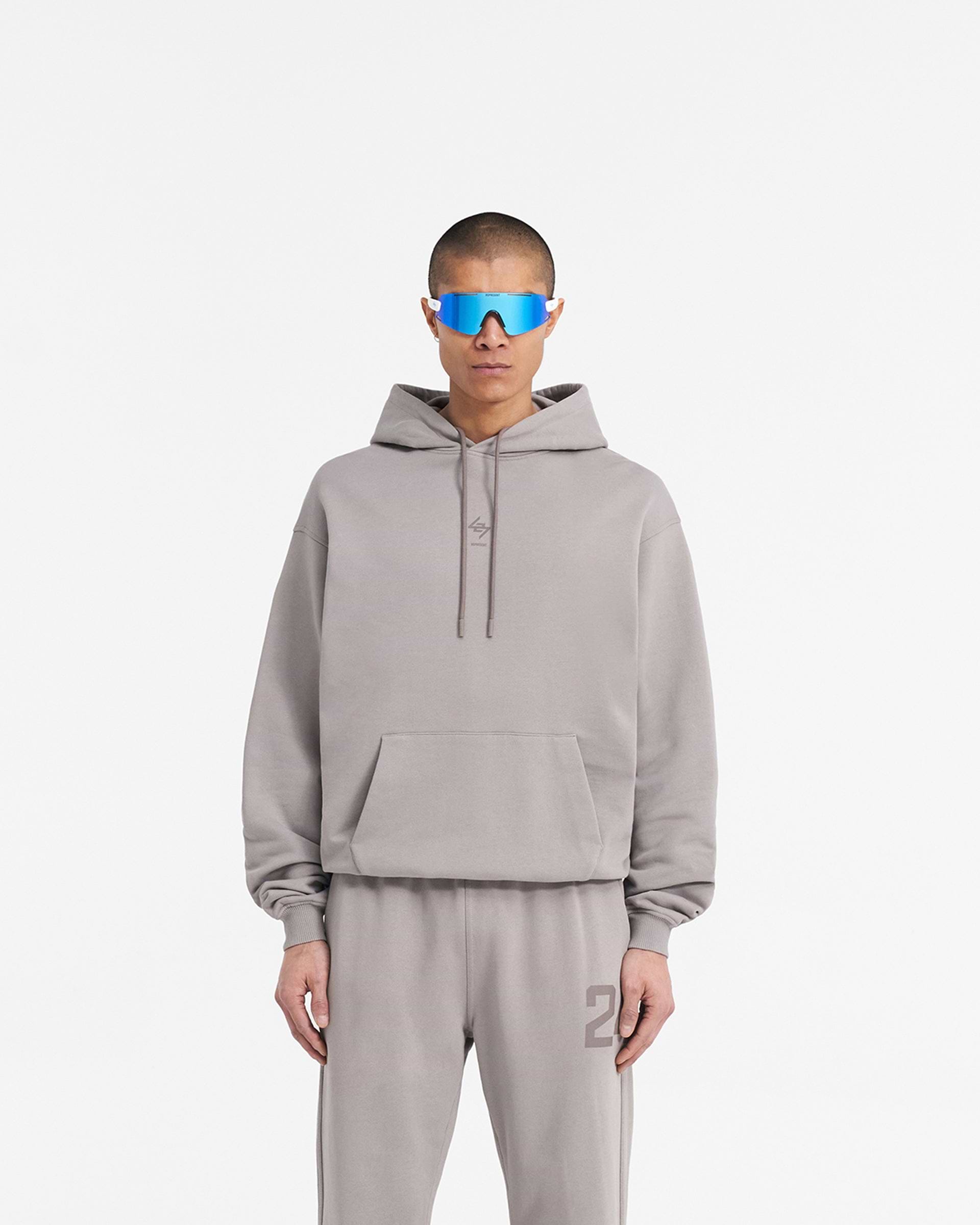 Man wearing an oversized grey hoodie on a plain white background | 247 Oversized Hoodie in Cinder | Hoodie with ribbed cuffs and hem | 247 Hoodies | Represent Clo