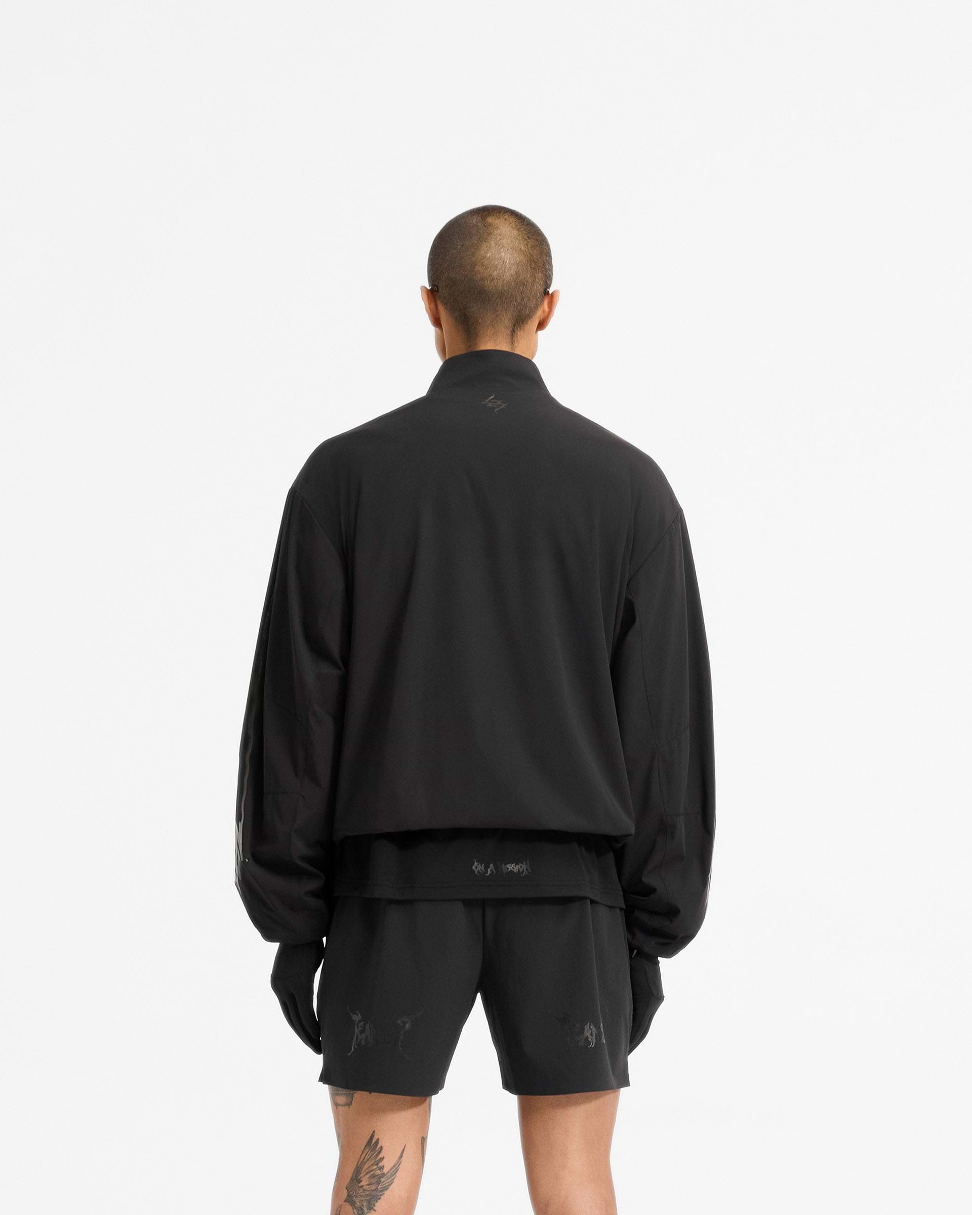 Man wearing a black track jacket on a plain white background | Team 247 X END Track Jacket in Jet Black | Track jacket with 4-way stretch nylon shell and mesh lining | 247 Outerwear | Represent Clo