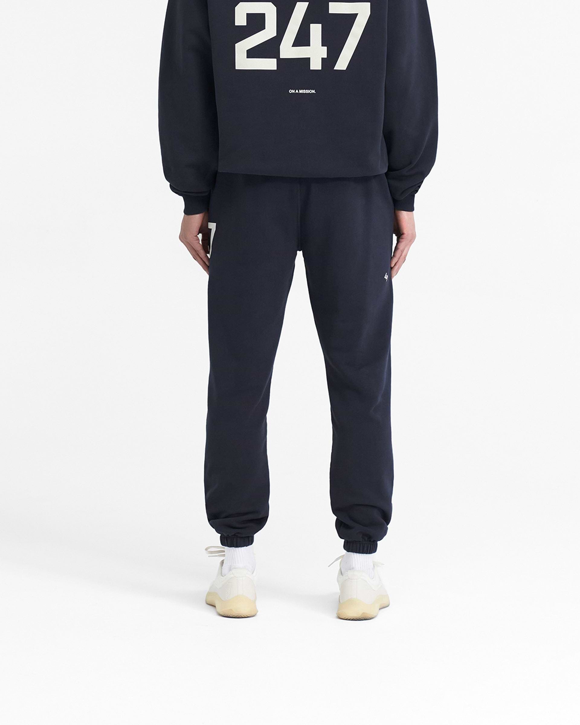Man wearing navy sweatpants on a plain white background | 247 Sweatpant in Navy | Training joggers with elasticated cuffs and drawcord waistband | 247 Pants | Represent Clo