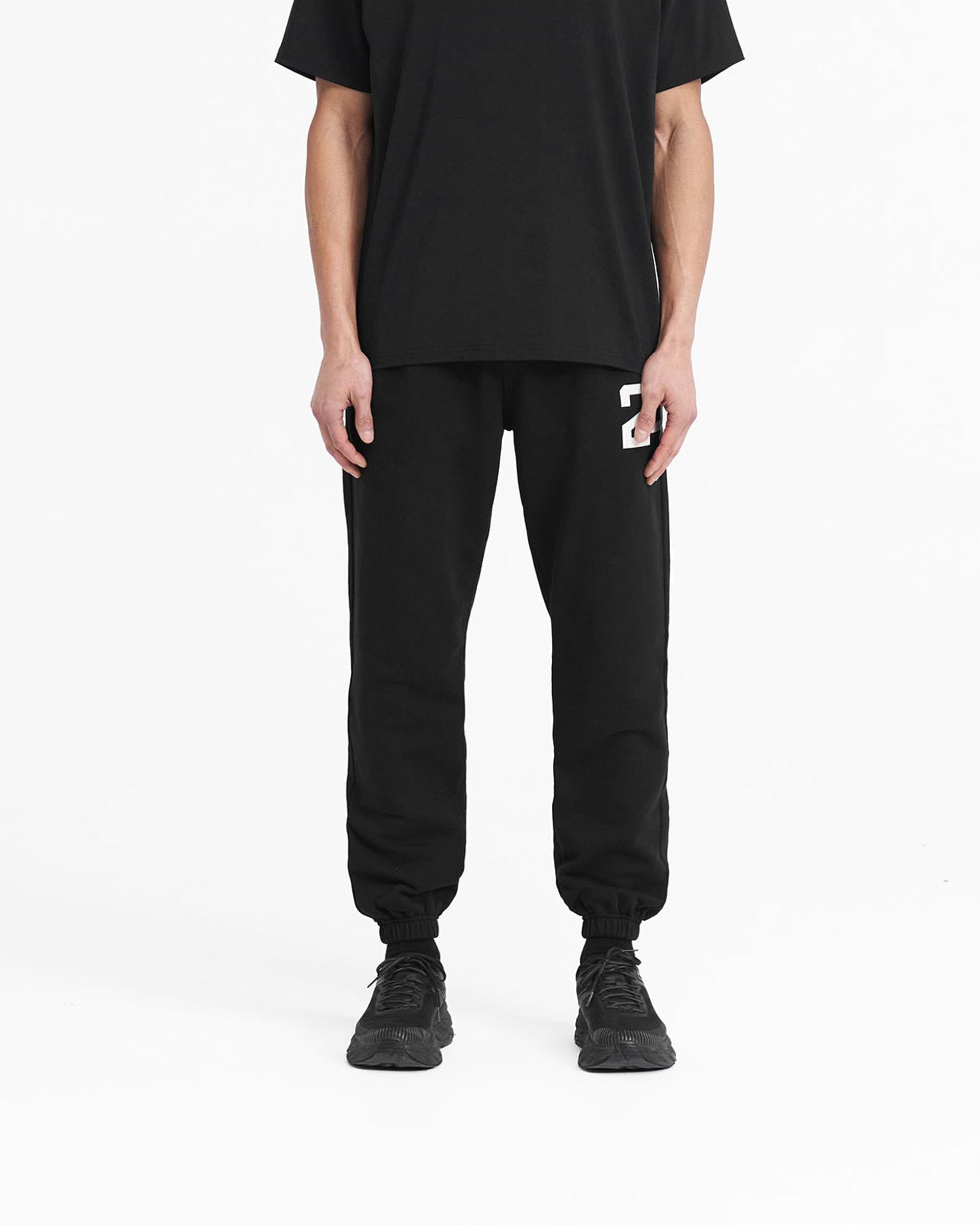 Man wearing black sweatpants on a plain white background | 247 Sweatpant in Black | Training joggers with elasticated cuffs and drawcord waist | 247 Pants | Represent Clo