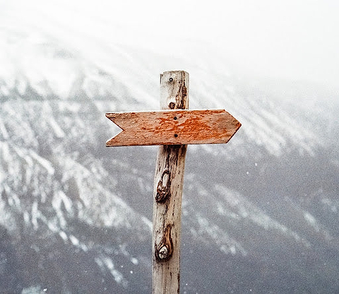 A brown wooden arrow sign