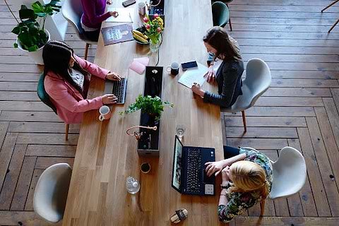 A group of women work at a desk