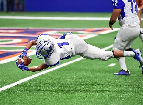 A football player diving and catching the ball