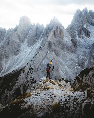 The best warm gear to help you prepare for winter. | Man stands on rock promontory looking at icy mountain peaks around him. | Heat Holders®