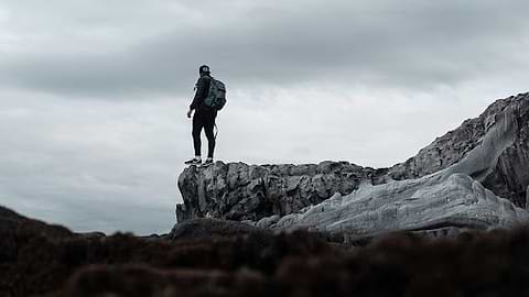 Essential warm gear for winter hiking for men. | Man stands on rock looking at the view in winter. | Heat Holders®