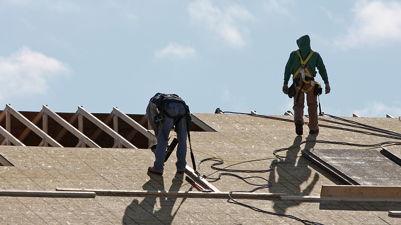 Two roofers work in the snow