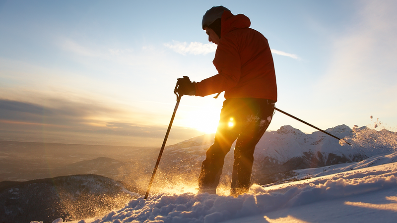 Skier looks down a hill as the sun sets