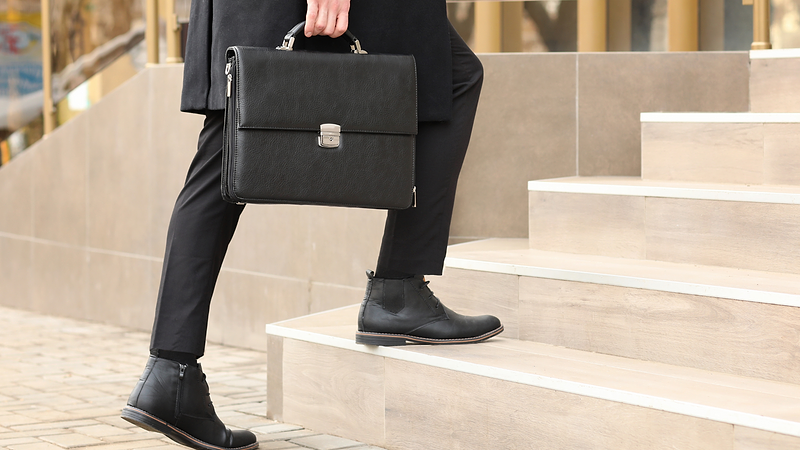 Man carrying a briefcase walks up stairs outside and office building