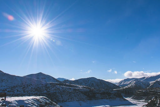 Sun shines brilliantly in a blue sky over mountains