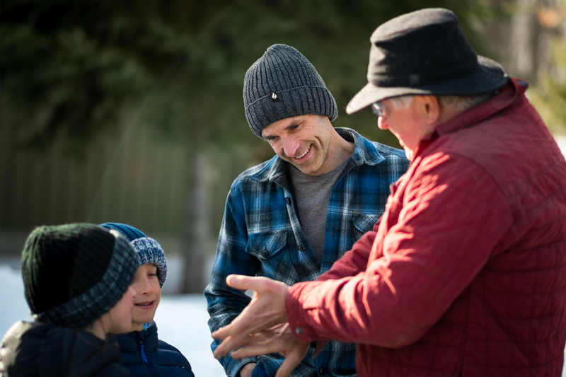 Grandfather, father, and two sons talking outside.