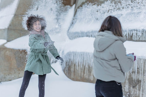 Two women play in the snow. | Heat Holders® Merino Socks