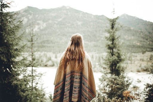 Woman wearing poncho looks out on a mountain landscape in winter. | Heat Holders® thermal socks