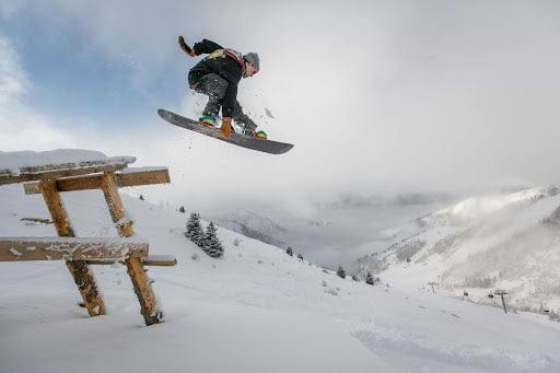 Snow boarder performs a jump off of a ramp.