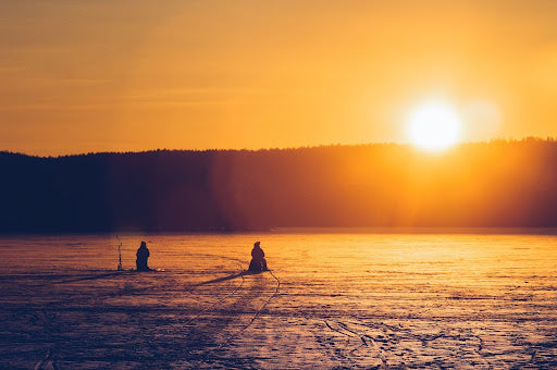 Two men ice fishing on a frozen lake. | Heat Holders®