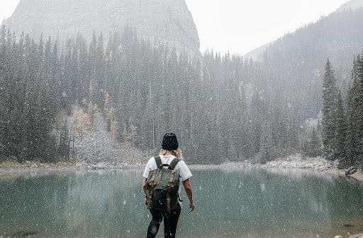 Woman hikes by a lake in winter. Heat Holders® thermal hats