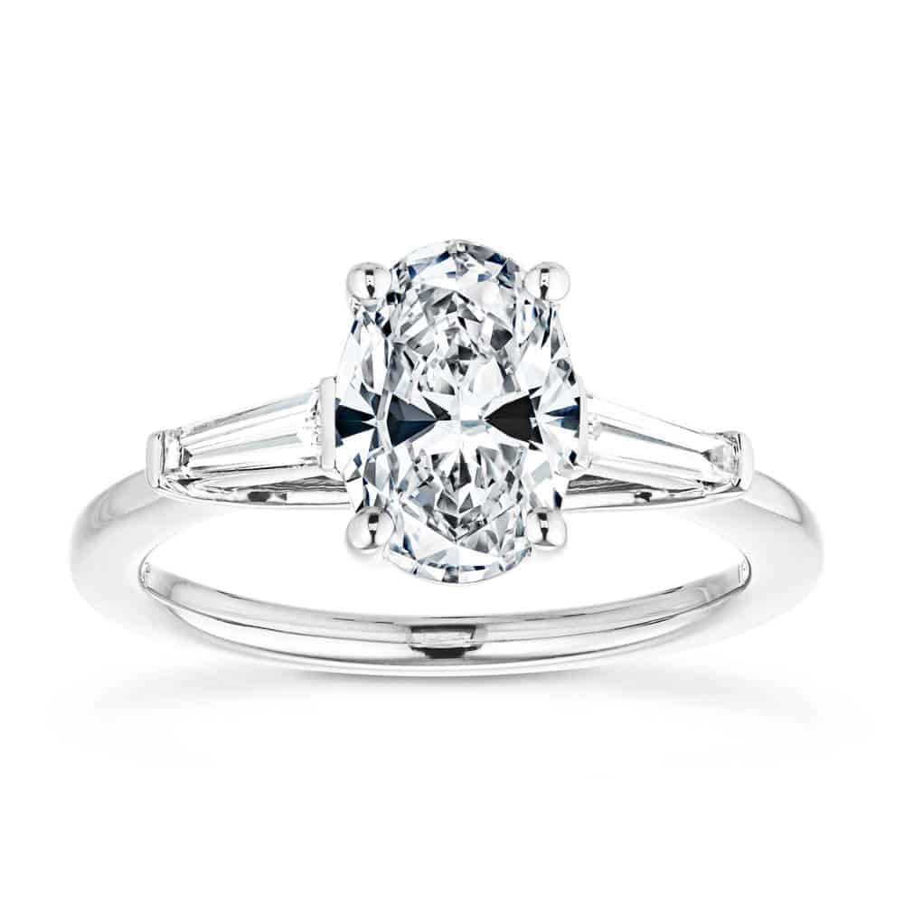 Shown with 2ct Oval Cut Lab Grown Diamond set in 14k White Gold|Beautiful three stone engagement ring with trellis set 2ct oval cut lab grown diamond amid baguette side stones in 14k white gold