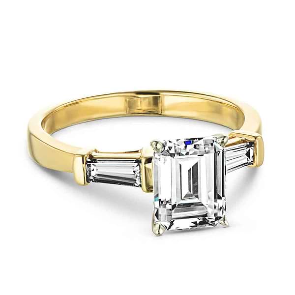 Shown with 1ct Emerald Cut Lab Grown Diamond in 14k Yellow Gold|Modern three stone engagement ring with two baguette cut recycled diamond side stones and a 1ct emerald cut lab grown diamond center in 14k yellow gold