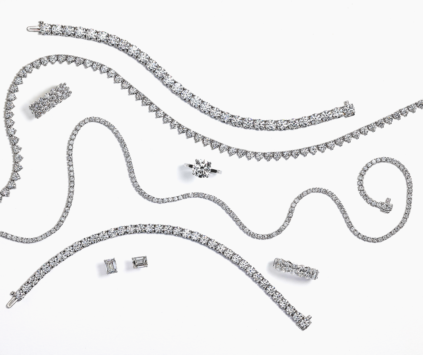 Collection of diamond jewelry including necklaces and earrings on a white background