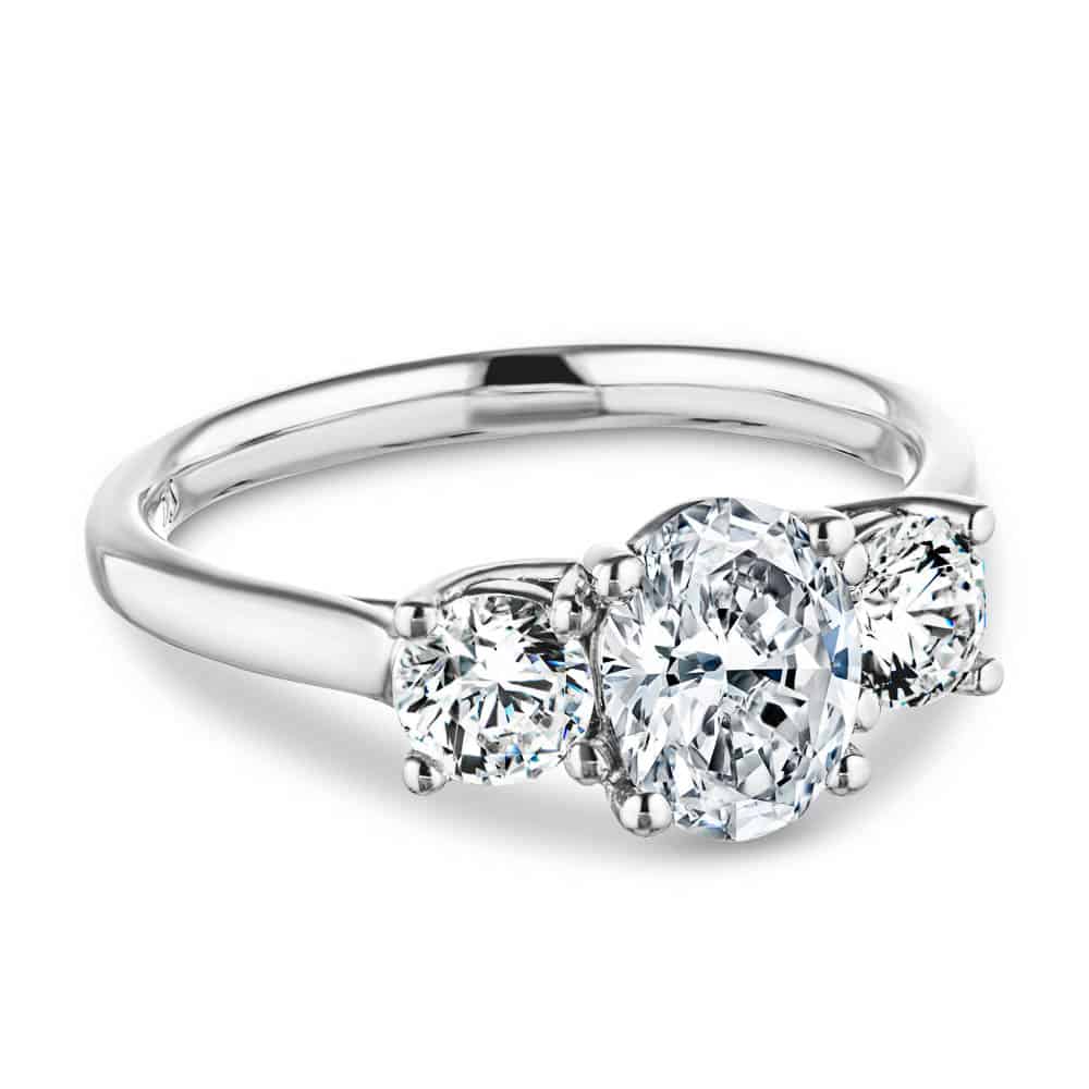 Shown with 1ct Oval Cut and Two 0.5ct Round Cut Lab Grown Diamonds in 14k White Gold|Romantic three stone engagement ring with 1ct oval cut lab grown diamond and two 0.5ct round cut lab diamond side stones in 14k white gold