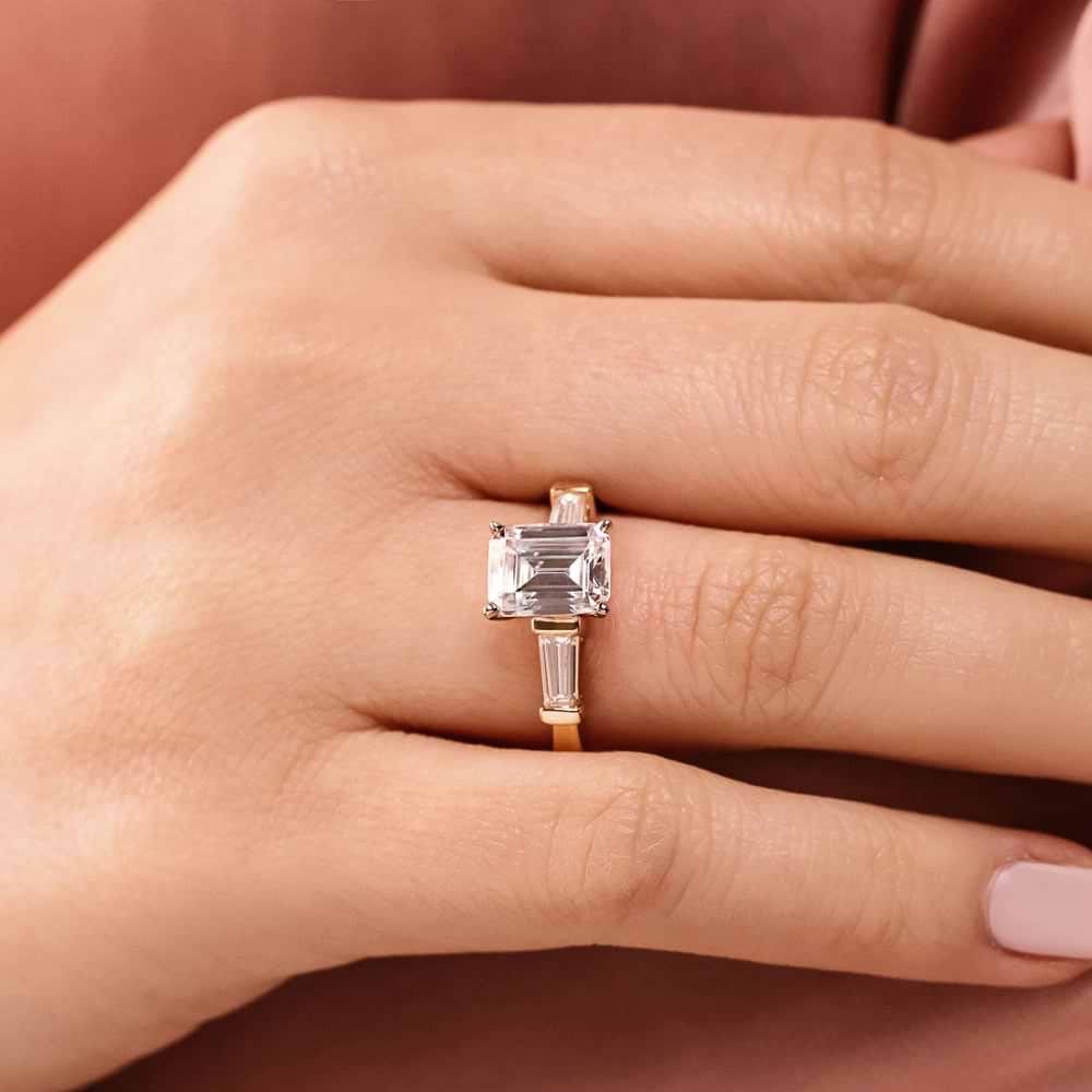 Shown In 14K Yellow Gold With An Emerald Cut Center Stone