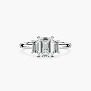 3 stone engagement ring shown in white gold with a lab grown diamond emerald cut center stone