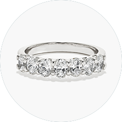 A platinum wedding band lined with seven oval-cut lab created diamonds.