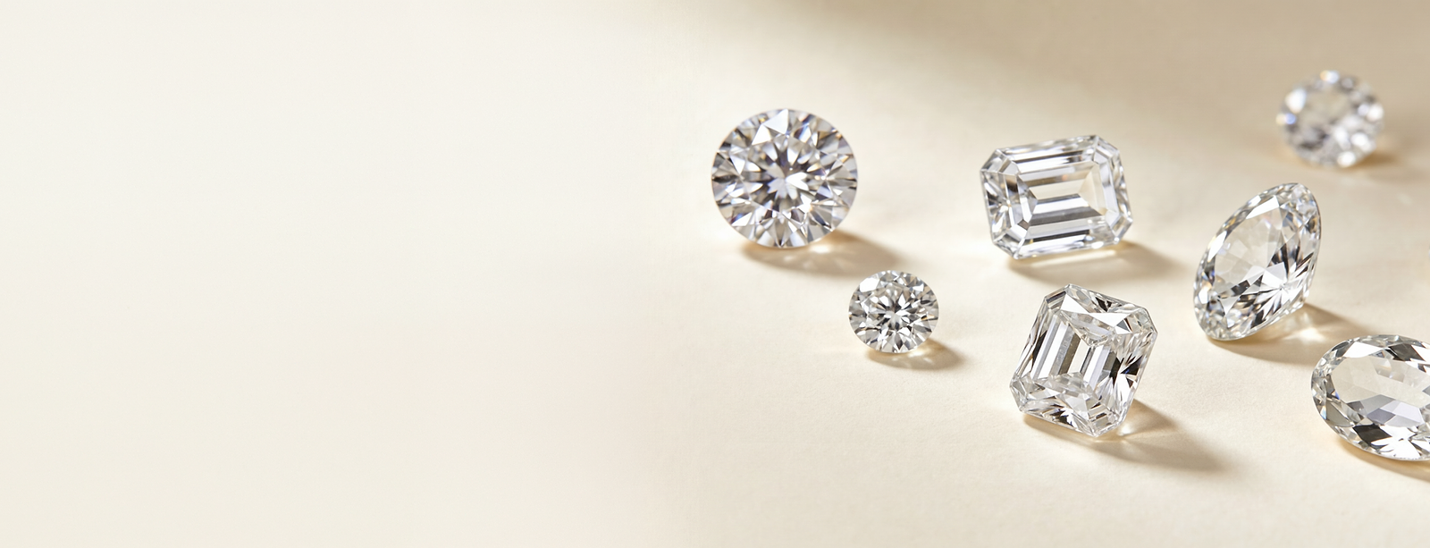 Collection of lab-grown diamonds in various cuts on a light beige background