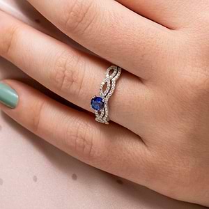 Vintage style diamond accented engagement ring with 1ct round cut lab created blue sapphire in 14k white gold worn on hand with matching band