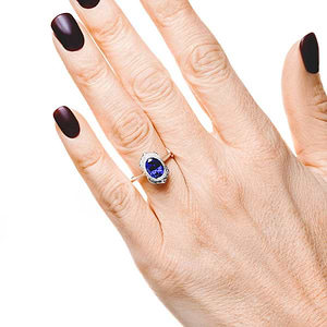 Antique style engagement ring with diamond halo and bezel set 2ct oval cut lab grown blue sapphire in 14k white gold worn on hand