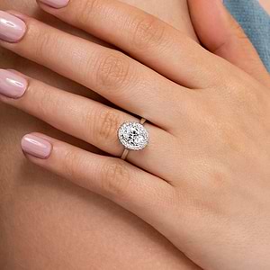 Antique style diamond accented halo engagement ring with 1ct oval cut lab grown diamond in 14k white gold shown worn on hand