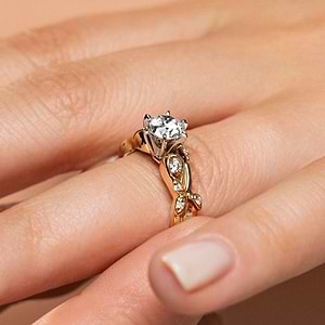 Nature inspired design engagement ring with diamond accented band and a 1ct round cut lab created diamond in 14k yellow gold shown worn on hand