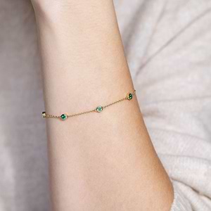 Woman wearing Emerald Bezel Station Chain Bracelet in 14 carat Yellow Gold from Lab Grown Gemstone specialists MiaDonna 