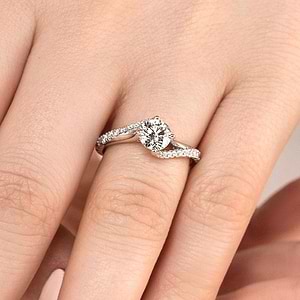 Modern diamond accented engagement ring with twisted band set with 1ct round cut lab grown diamond in 14k white gold worn on hand
