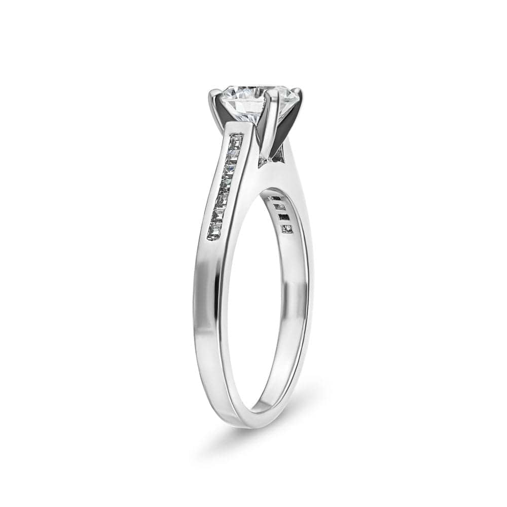 Shown with 1ct Round Cut Lab Grown Diamond in Platinum|Modern style diamond accented engagement ring with 1ct round cut lab grown diamond and channel set princess cut accenting side stones in platinum