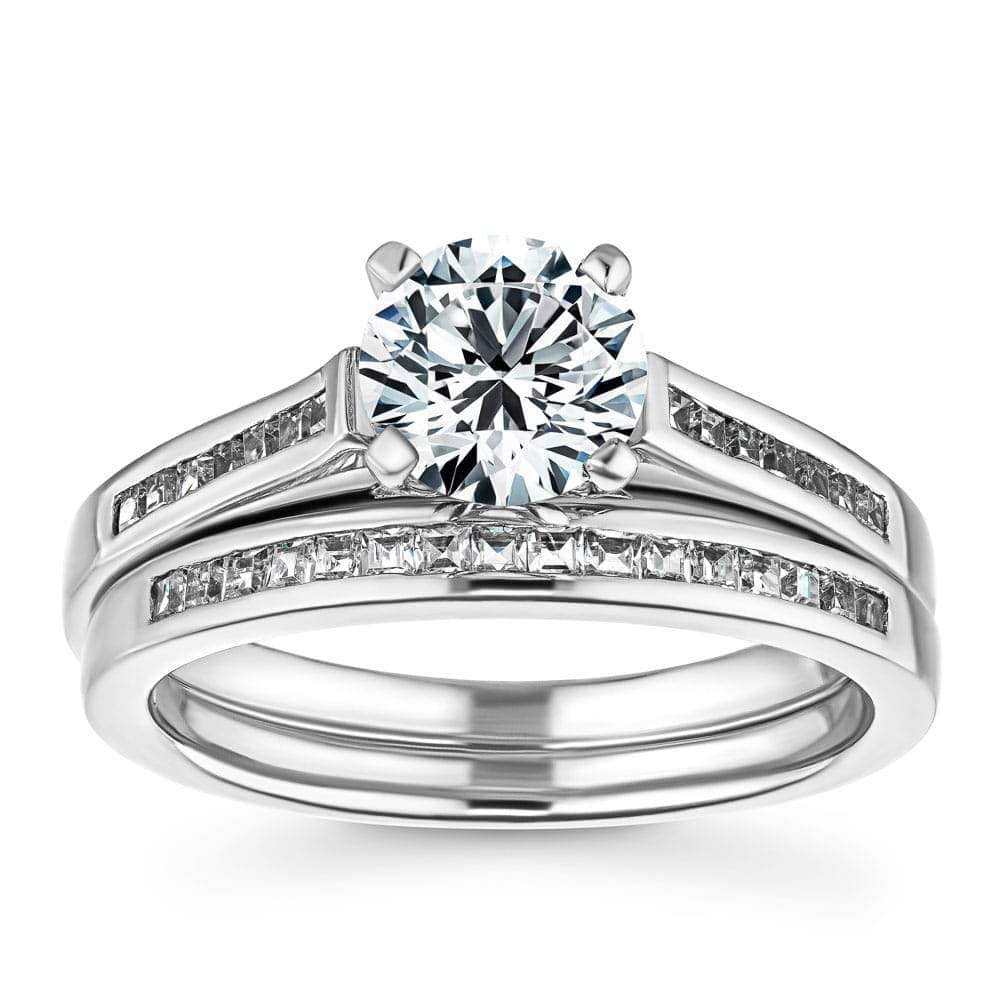 Shown with a 1.0ct Round cut Lab Grown Diamond with channel set diamond accented band with matching wedding band in recycled 14K white gold 