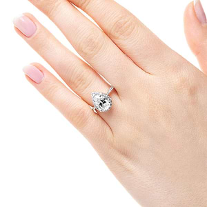 Diamond accented halo engagement ring with 1ct pear cut lab grown diamond in 14k white gold worn on hand