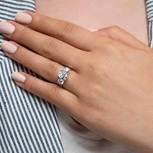 Conflict free three stone engagement ring with 1ct oval cut lab grown diamond and two 0.5ct round cut lab diamond side stones in 14k white gold worn on hand