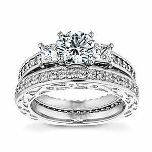  three stone engagement ring Shown with round cut center stone and two Princess cut Lab-Grown Diamonds with scroll detailing and accenting diamonds on the band in recycled 14K white gold with matching wedding band