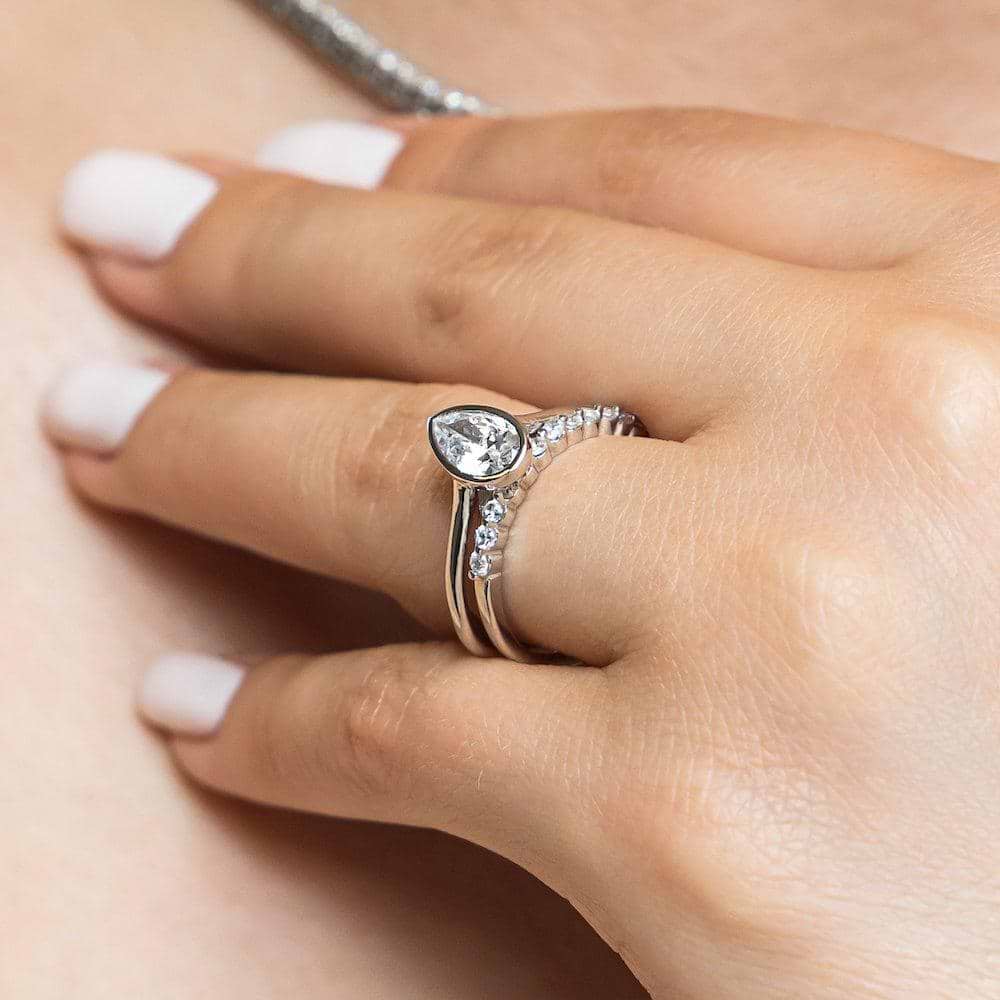 Shown with a bezel set 1.0ct Pear cut Lab-Grown Diamond in recycled 14K white gold with the matching diamond accented band, can be purchased as a set for a discounted price 
