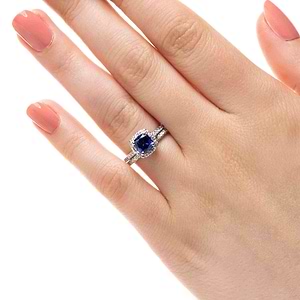  diamond halo accented engagement ring Shown with a 1.0ct Cushion cut Blue Sapphire Lab-Created gemstone with a diamond accented halo and diamonds accenting the band in recycled 14K white gold with matching band