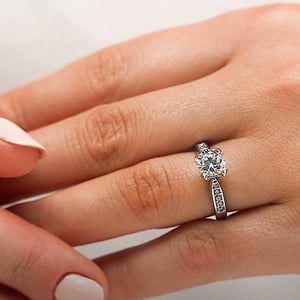 Channel set diamond accented engagement ring with 1ct round cut lab grown diamond and peek-a-boo diamonds in 14k white gold shown worn on hand