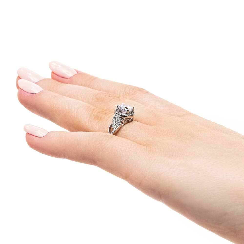 Shown with 1ct Round Cut Lab Grown Diamond in 14k White Gold|Vintage style diamond accented halo engagement ring with 1ct round cut lab created diamond with milgrain and filigree detailing in two tone 14k white gold worn on hand