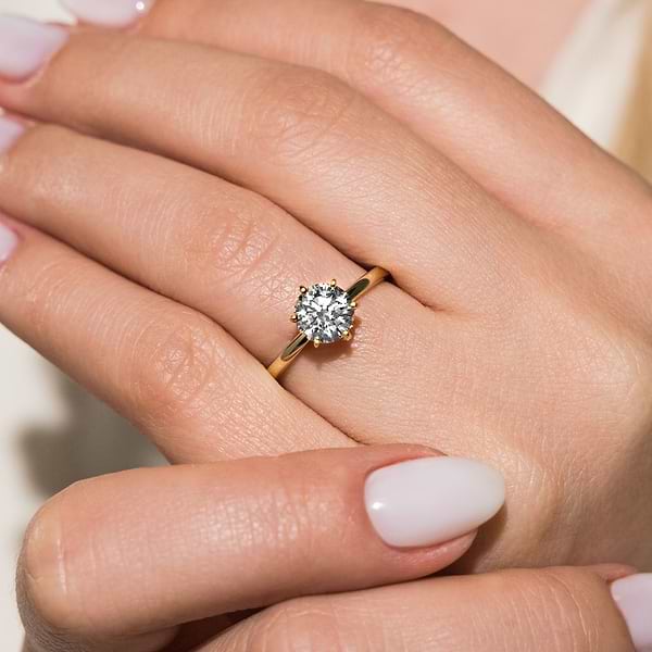 Traditional solitaire engagement ring shown here with a 1.5ct round lab-grown diamond in a six prong yellow gold setting. | Lab-grown diamond yellow gold six prong solitaire engagement ring